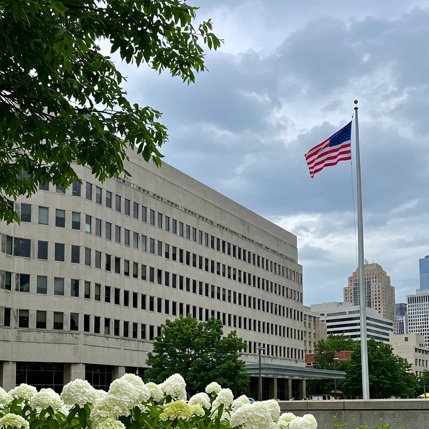 American flag flying on tall commercial flagpole in front of downtown office building